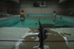 Casal homoafetivo distante em piscina olímpica rasa e rachada, simbolizando relações rasas e vazio emocional.