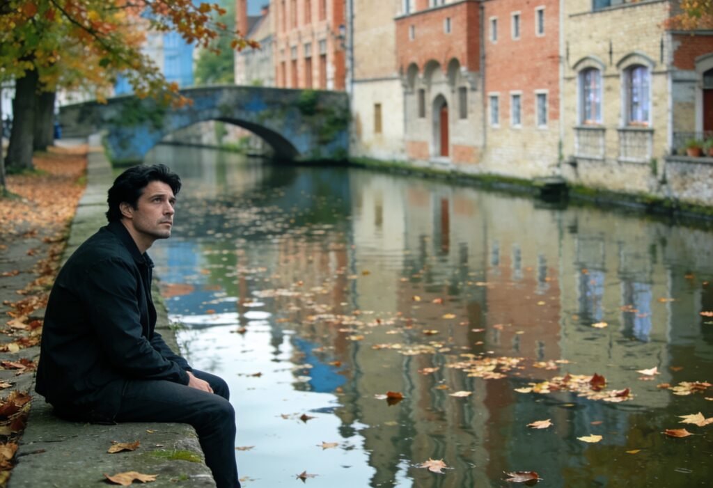 O que é ressentimento: homem sentado sozinho à beira de um canal em cidade europeia no outono, olhando para cima, pensativo