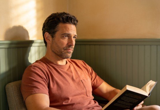 inteligência emocional existe: homem sentado lendo um livro com expressão pensativa e séria